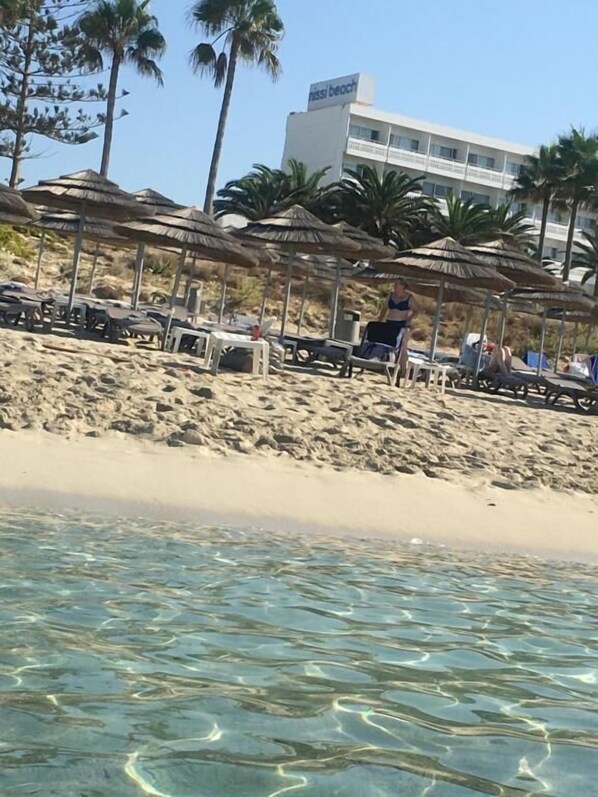 In Strandnähe, weißer Sandstrand, Liegestühle, Sonnenschirme