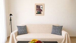Un soggiorno con un divano, una ciotola di frutta su un tavolo, una lampada da terra e un quadro appeso al muro.