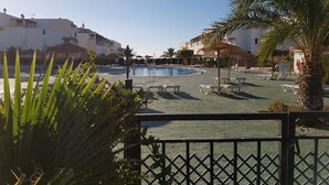 A pool area with lounge chairs and palm trees, surrounded by buildings. - Extraordinary duplex in Naturist area (Vera)