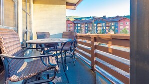 A balcony with wicker furniture and a view of colorful buildings in the background. - Stunning mountain view, free wifi, underground parking (copper mountain)