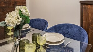 A dining area with a cityscape painting, a table set with plates, glasses, and a vase of flowers.