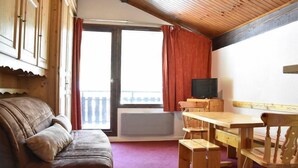 Ein gemütliches Zimmer mit einem braunen Ledersofa, Holztischen und einem Fernseher.