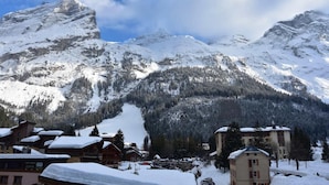 Ein Bergdorf mit schneebedeckten Häusern und einem markanten Berggipfel im Hintergrund.