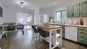 Una cocina moderna con una isla de madera, taburetes de bar y armarios verdes.