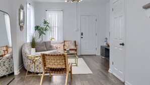 Una sala de estar con sofá, sillones, una mesita de centro, una planta y un mueble para televisión.