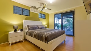 A bedroom with a bed, nightstands, an air conditioner, a ceiling fan, and a window with blinds. - 7 Skipjack Circle - Central Location (Exmouth)