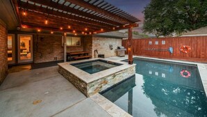 Un espace piscine extérieur moderne, agrémenté d’une pergola, d’un jacuzzi et d’une clôture en bois.