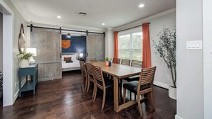 Un coin repas avec une table et des chaises en bois, un banc et une vue sur l’extérieur par une fenêtre.