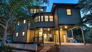 A multi-story house with a porch, a garage, and a driveway.