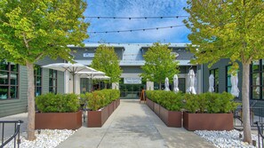 A modern outdoor cafe area with a pathway leading to a building entrance, surrounded by planters and umbrellas. - Private Pool, Easy Walk to Beach, 5 Bikes + Free Dolphin Cruise! (Santa Rosa Beach)