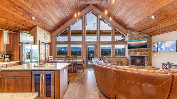 Una cocina amplia con una isla grande, techo de madera y grandes ventanales con vistas a la montaña.