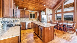 Una cocina amplia con armarios de madera, una isla grande y un comedor con vistas a las montañas.