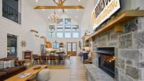A spacious living room with a fireplace, a dining area, and a kitchen.