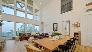 A spacious living area with a large wooden dining table, leather sofas, and a view of the outdoors.
