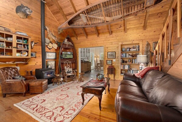 A cozy log cabin interior with a fireplace, leather furniture, and rustic decor.
