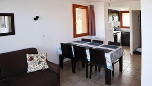 A compact living space with a dining area, kitchenette, and a sofa with a floral cushion. - Ski-in/ski-out & foot of the slopes, swimming pool, sauna, hammam, terrace, tv, ski locker, 43m² (Les Orres)
