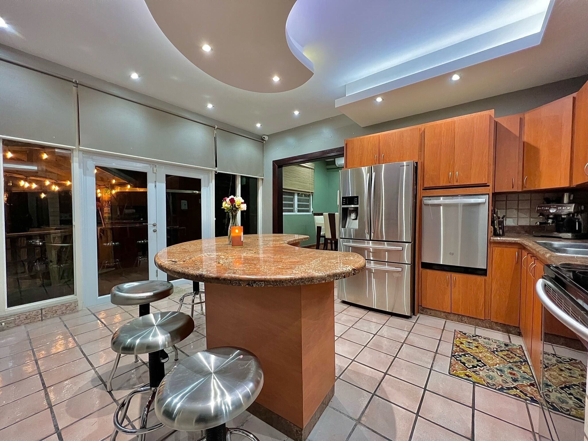 Uma cozinha moderna com ilha central, eletrodomésticos de aço inoxidável e um espaço de jantar com banquetas.