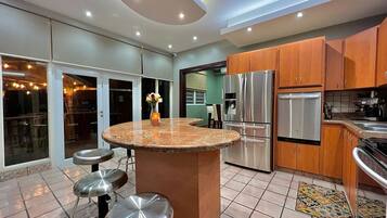Uma cozinha moderna com ilha central, eletrodomésticos de aço inoxidável e um espaço de jantar com banquetas.
