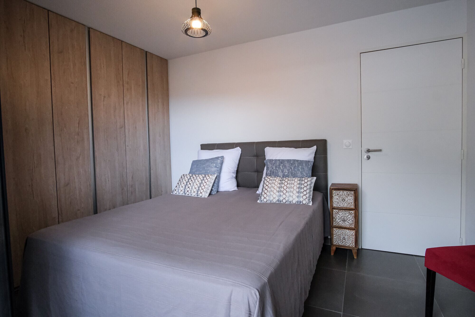 Een slaapkamer met een bed, een kledingkast, een nachtkastje en een deur.