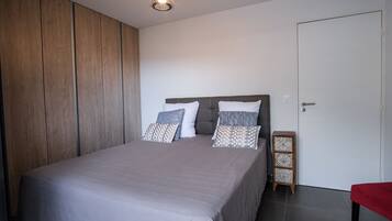 Een slaapkamer met een bed, een kledingkast, een nachtkastje en een deur.