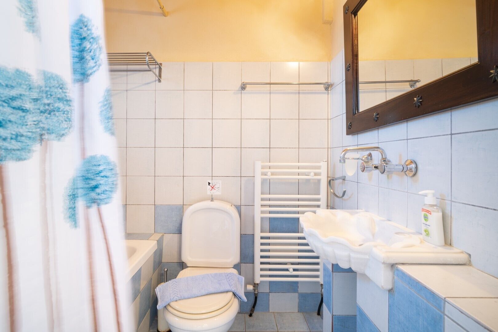 Un baño con inodoro, lavamanos y perchero para toallas.