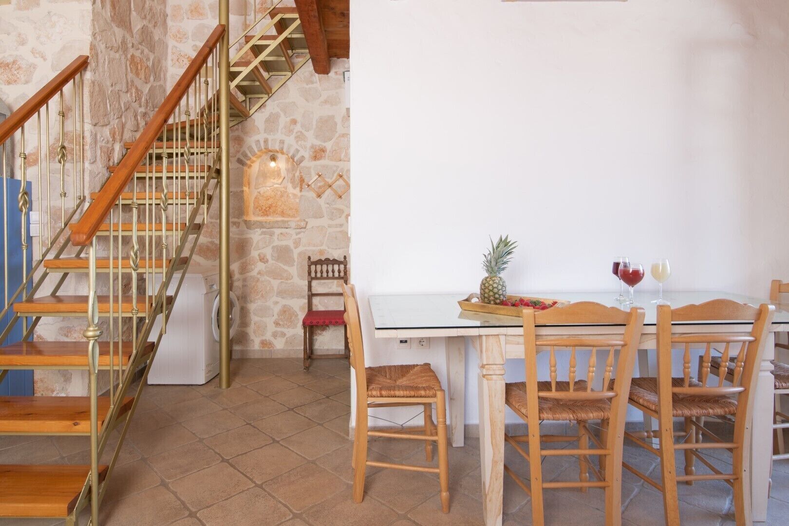 A dining area with a table set for two, a wooden chair, and a stone wall.