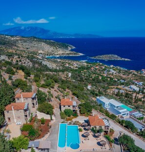 An aerial view of a coastal property with a swimming pool, stone buildings, and a view of the sea and mountains. - Strofilia Authentic Villas (Zakynthos)