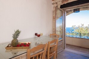 A balcony with a table, chairs, a tray of fruit, and wine glasses. - Strofilia Authentic Villas (Zakynthos)