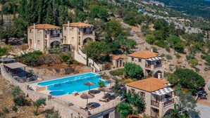 A hillside hotel with stone buildings, a swimming pool, and a view of the surrounding landscape. - Strofilia Authentic Villas (Zakynthos)
