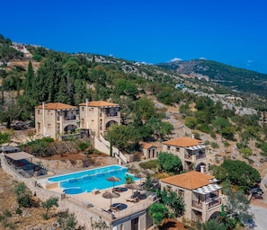A hillside hotel with stone buildings, a swimming pool, and a view of the surrounding landscape. - Strofilia Authentic Villas (Zakynthos)