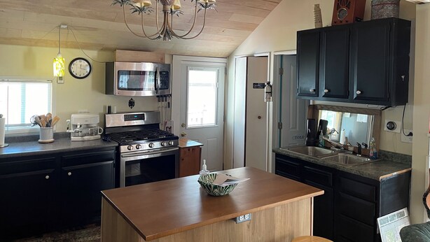 Una cucina con soffitto in legno, un lampadario, un forno a microonde, un piano cottura e mobili.