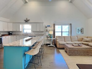 A spacious kitchen with a central island, white cabinetry, and a starfish decoration.