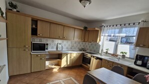 A kitchen with wooden cabinets, a microwave, an oven, and a sink. - Rural, by the North Sea, family-friendly, sauna and whirlpool! (Schiffdorf)