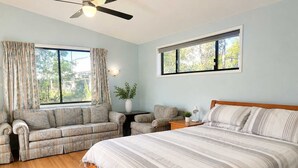 Un dormitorio con una cama grande, un sofá, una mesita y un ventilador de techo.