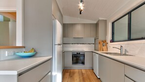 Una cocina moderna con horno empotrado, un lavamanos y una ventana.