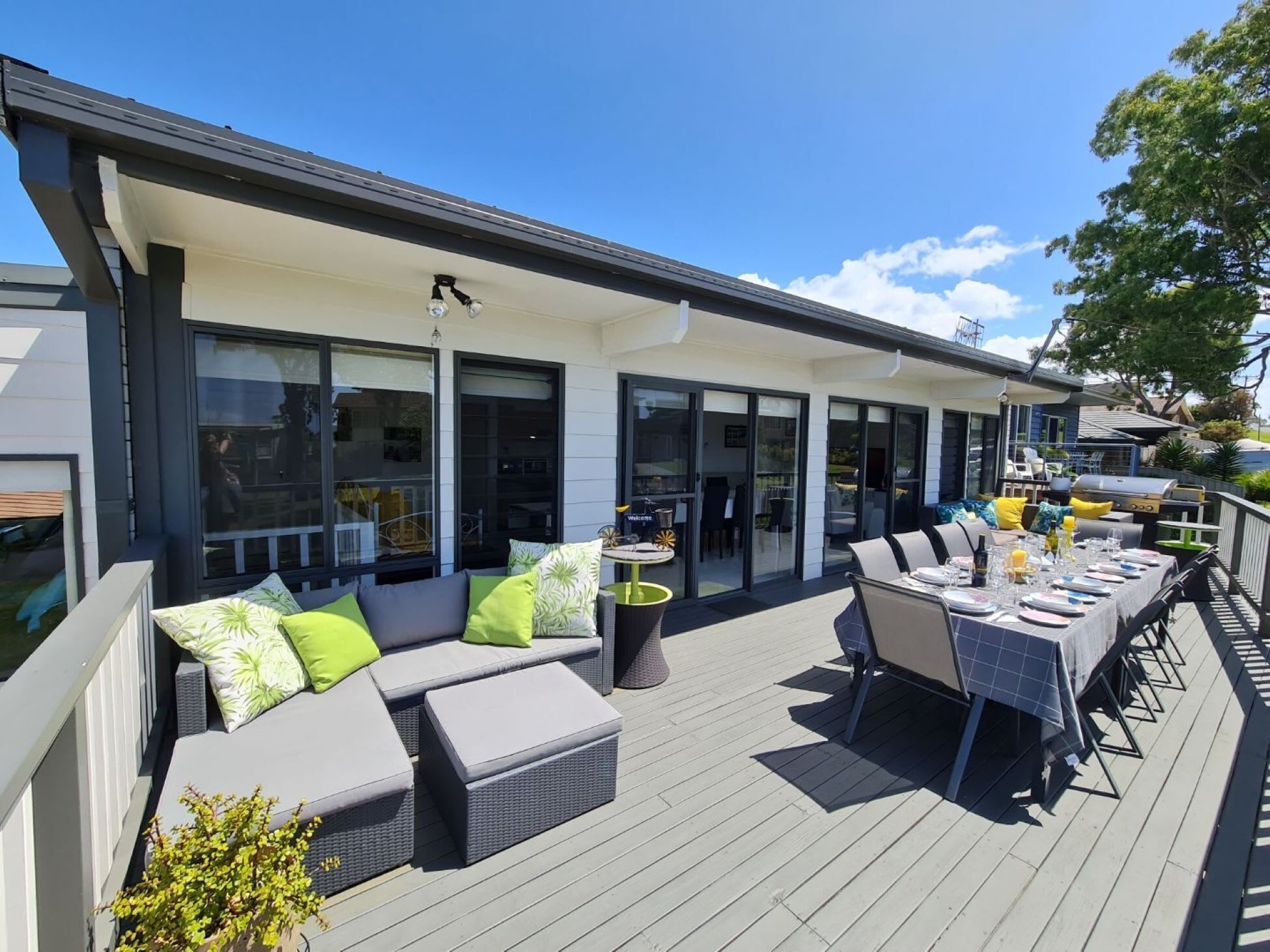 Eine überdachte Terrasse im Freien mit Esstisch, Stühlen und einer Couch mit Kissen.