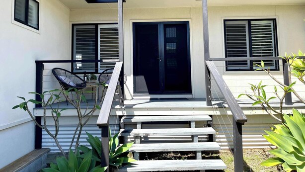 A modern house with a covered porch, a staircase, and a sliding glass door. - Sea Breeze On Carroll (Mollymook)