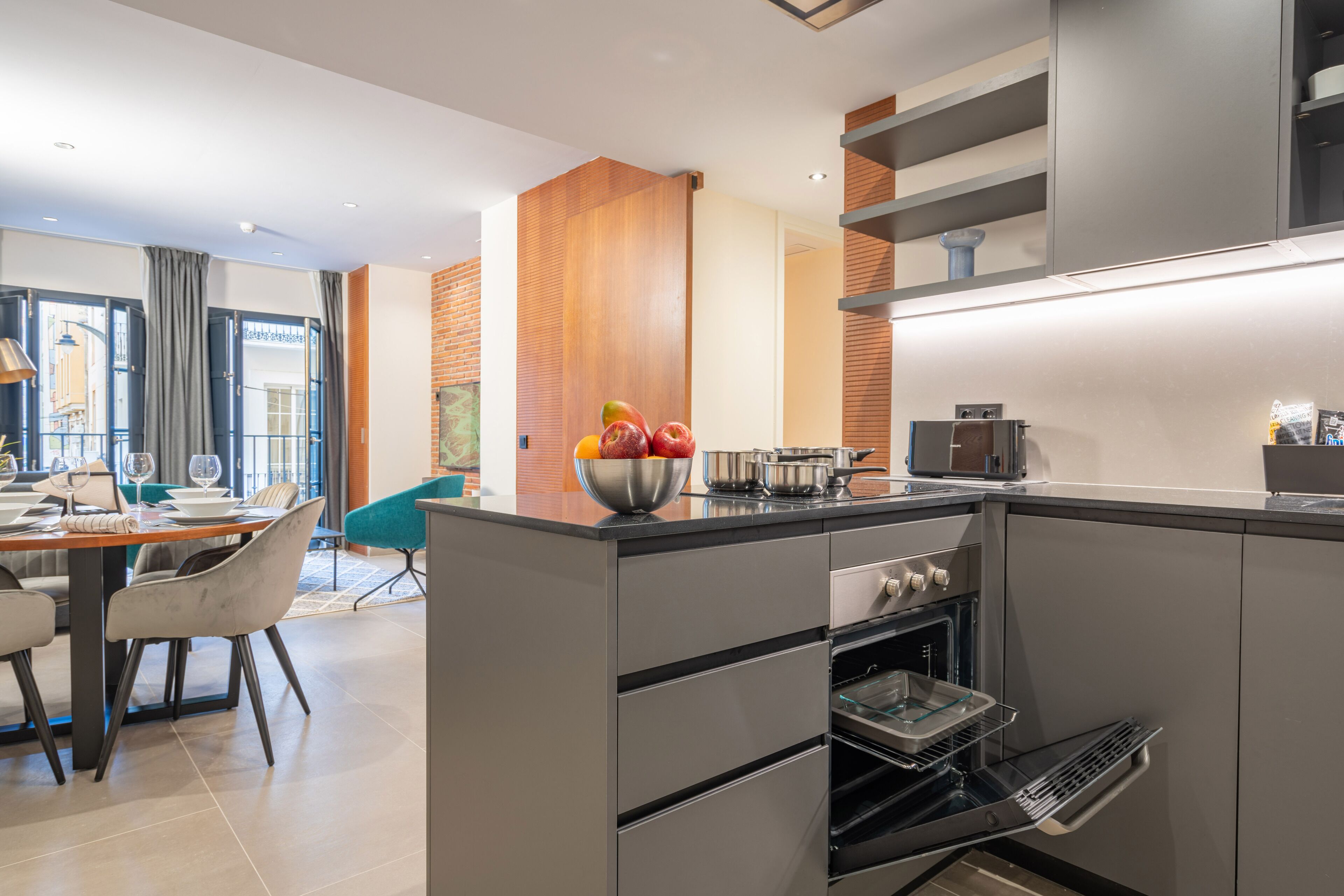 Une cuisine moderne dotée d’un îlot central, d’un four encastré et d’un coin repas avec une table et des chaises.