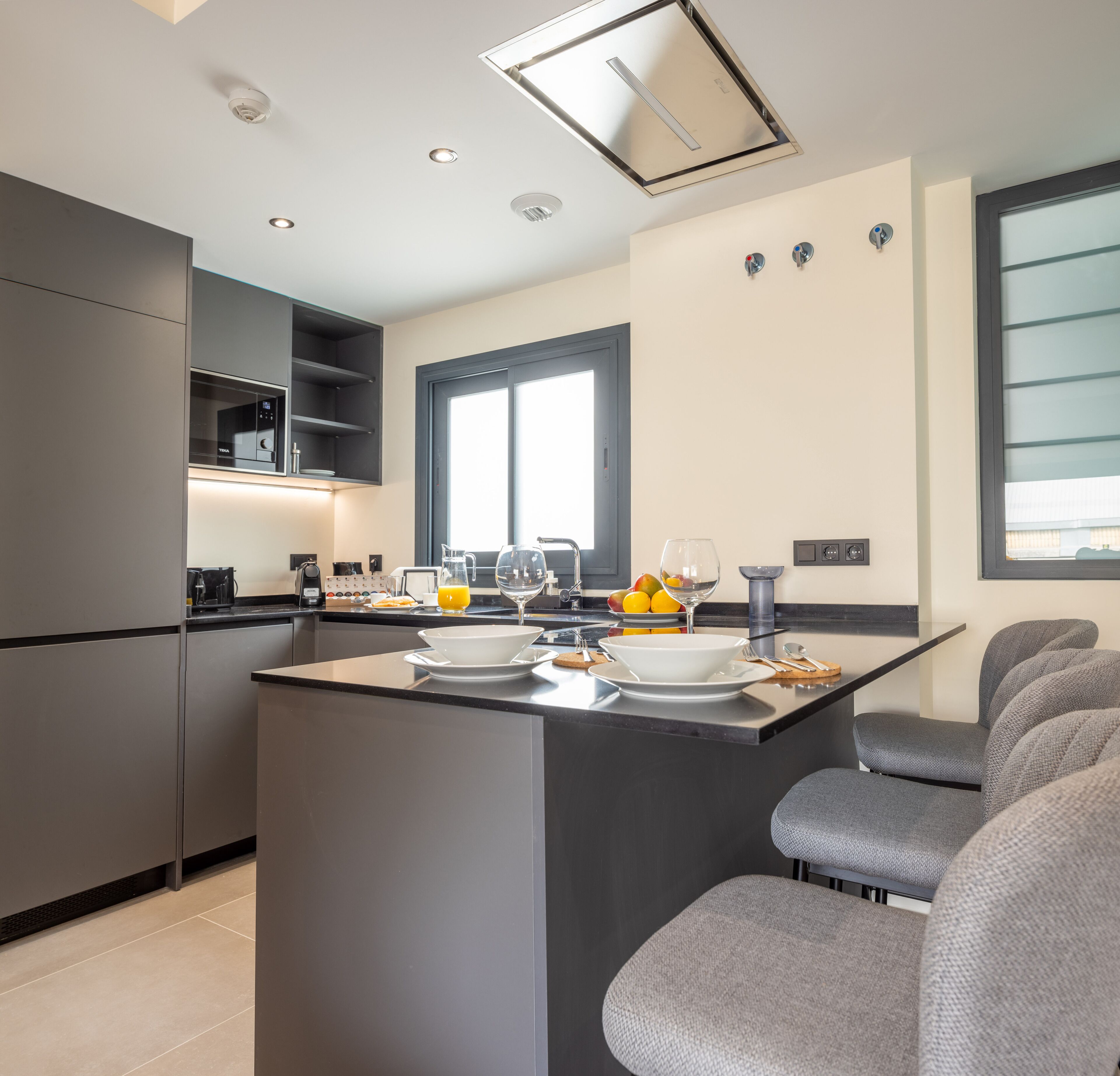 A modern kitchen with a central island, built-in appliances, and a large window.
