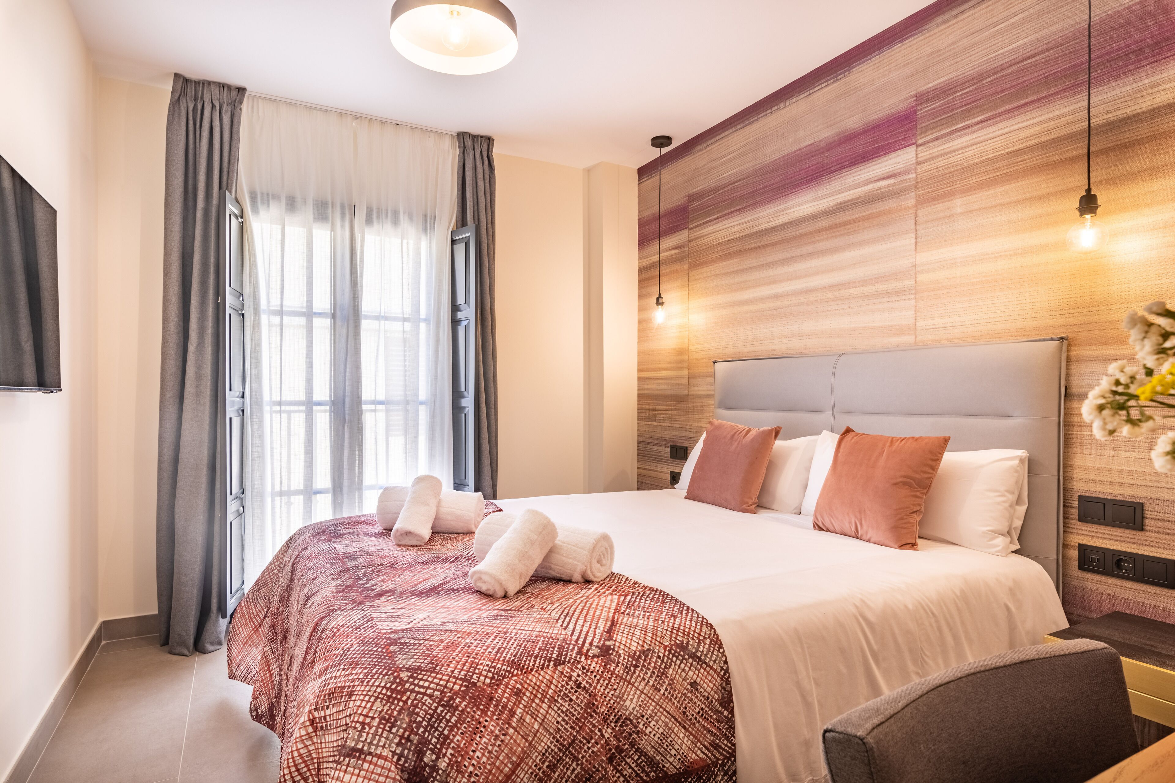 A modern hotel room with a large bed, a desk, and a window with curtains.