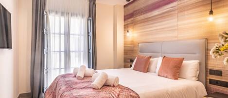 A modern hotel room with a large bed, a desk, and a window with curtains.