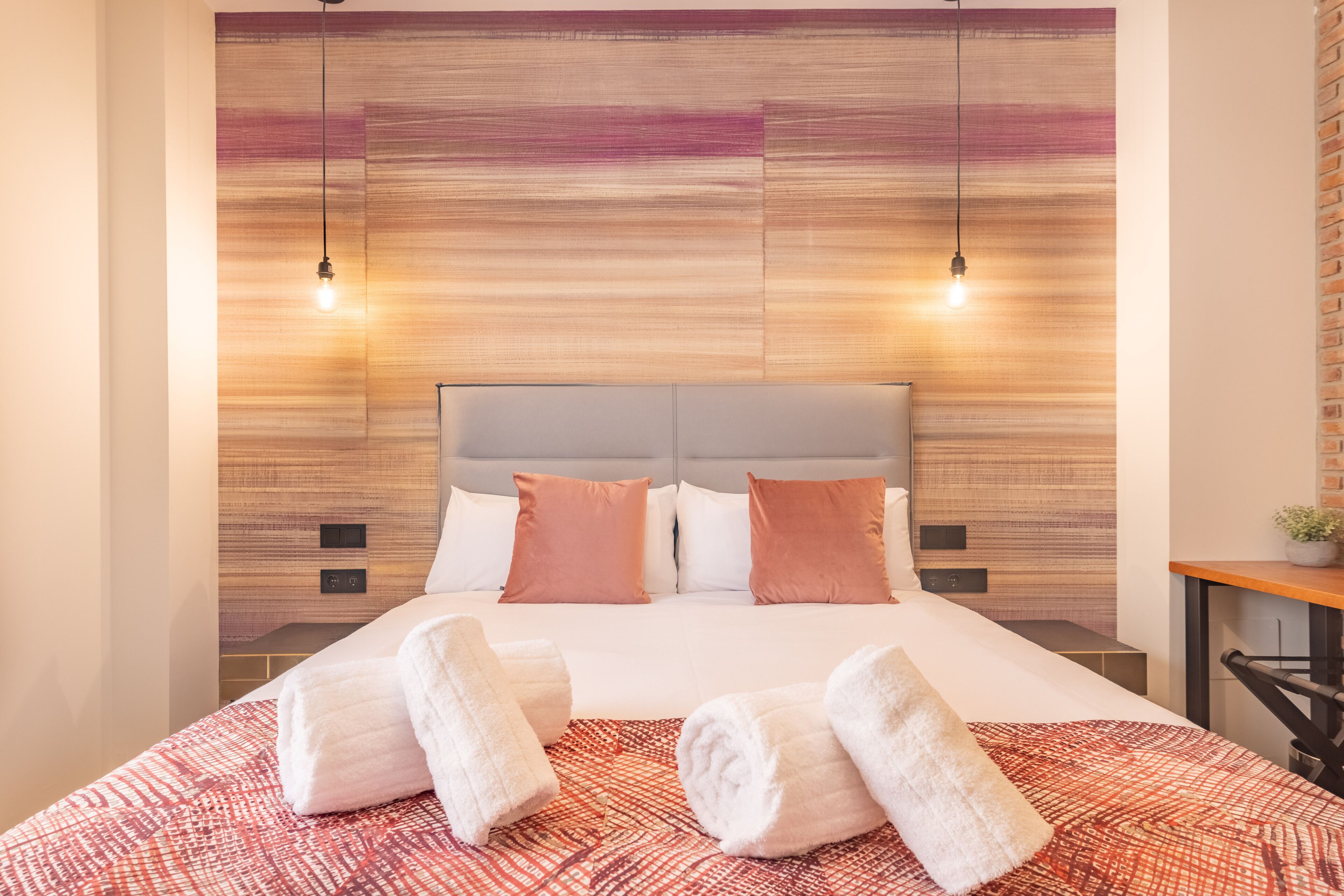 Une chambre d’hôtel avec un grand lit, deux lampes de chevet et une tête de lit en bois.