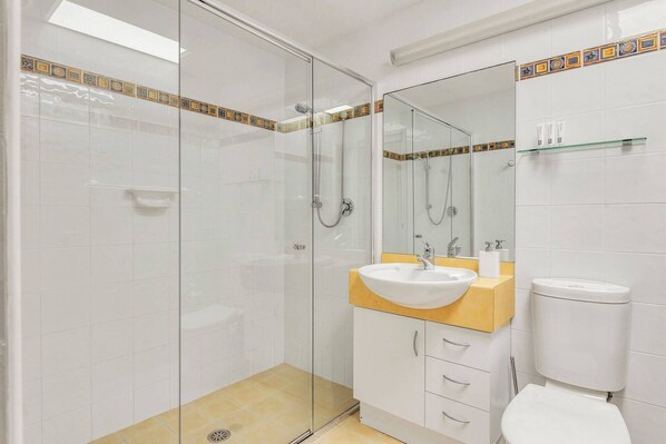 Ein Badezimmer mit Duschkabine, Waschbecken mit Spiegel und Toilette.