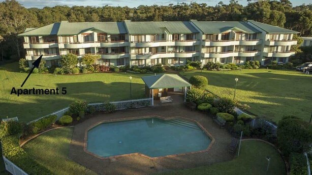 A multi-story hotel with a swimming pool and a covered patio area.