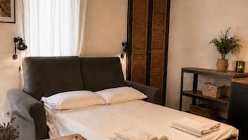 Ein Schlafzimmer mit Bett, Nachttisch, Lampe und einem Fenster mit Vorhängen.