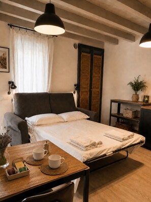 A bedroom with a bed, bedside table, lamp, and a window with curtains.