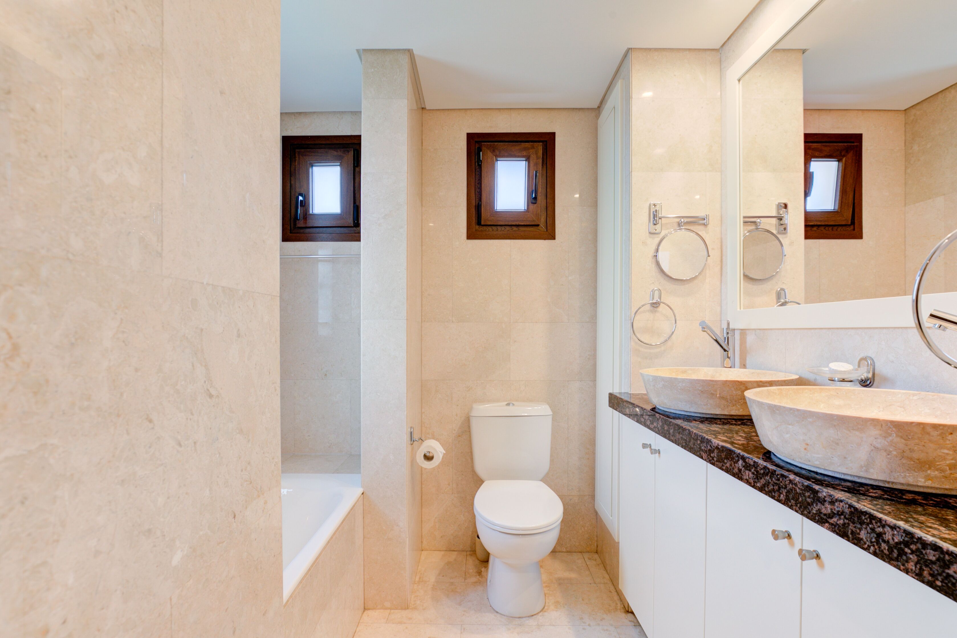 Une salle de bain moderne avec une baignoire, deux lavabos et des toilettes.