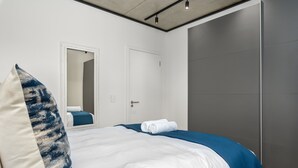 A modern bedroom with a bed, a large pillow, a folded towel, and a door. - 1 Bedroom on Century City Urban Square (Cape Town)