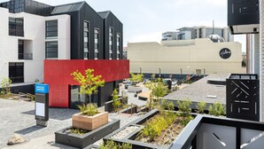 A modern building with a red facade and a sign for 'Bridge Water'. - 1 Bedroom on Century City Urban Square (Cape Town)