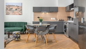 Una cocina moderna con gabinetes grises, lavadora integrada y un comedor con una mesa redonda y sillas.